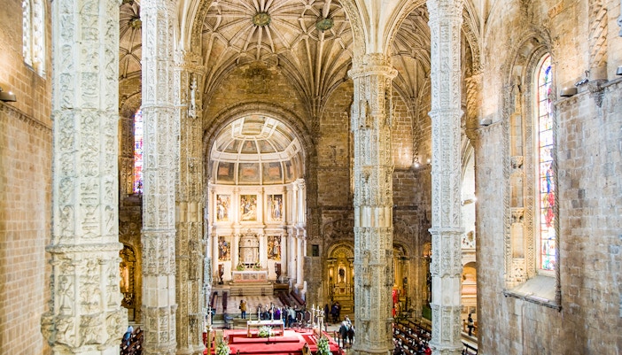 Jeronimos Monastery interior with ornate columns and altar in Lisbon.