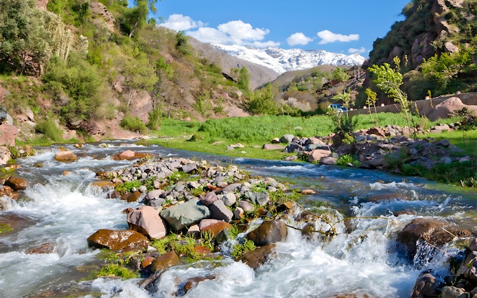 Setti Fatma waterfalls flowing through Ourika Valley, Morocco with lush greenery and distant mountains.