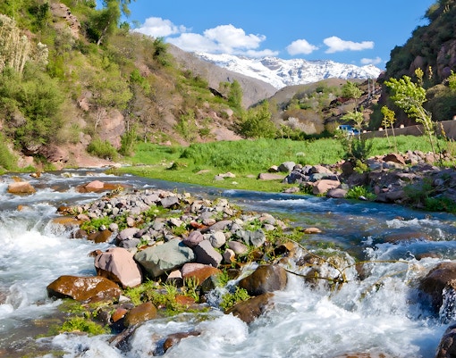Setti Fatma waterfalls flowing through Ourika Valley, Morocco with lush greenery and distant mountains.