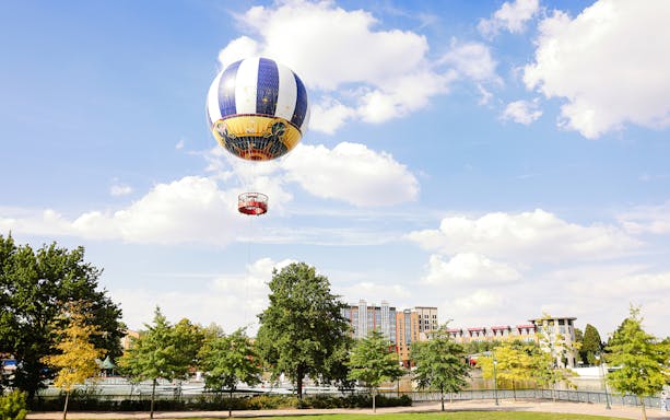 Balloon PanoraMagique floating over Disneyland Paris, France with trees and buildings below.
