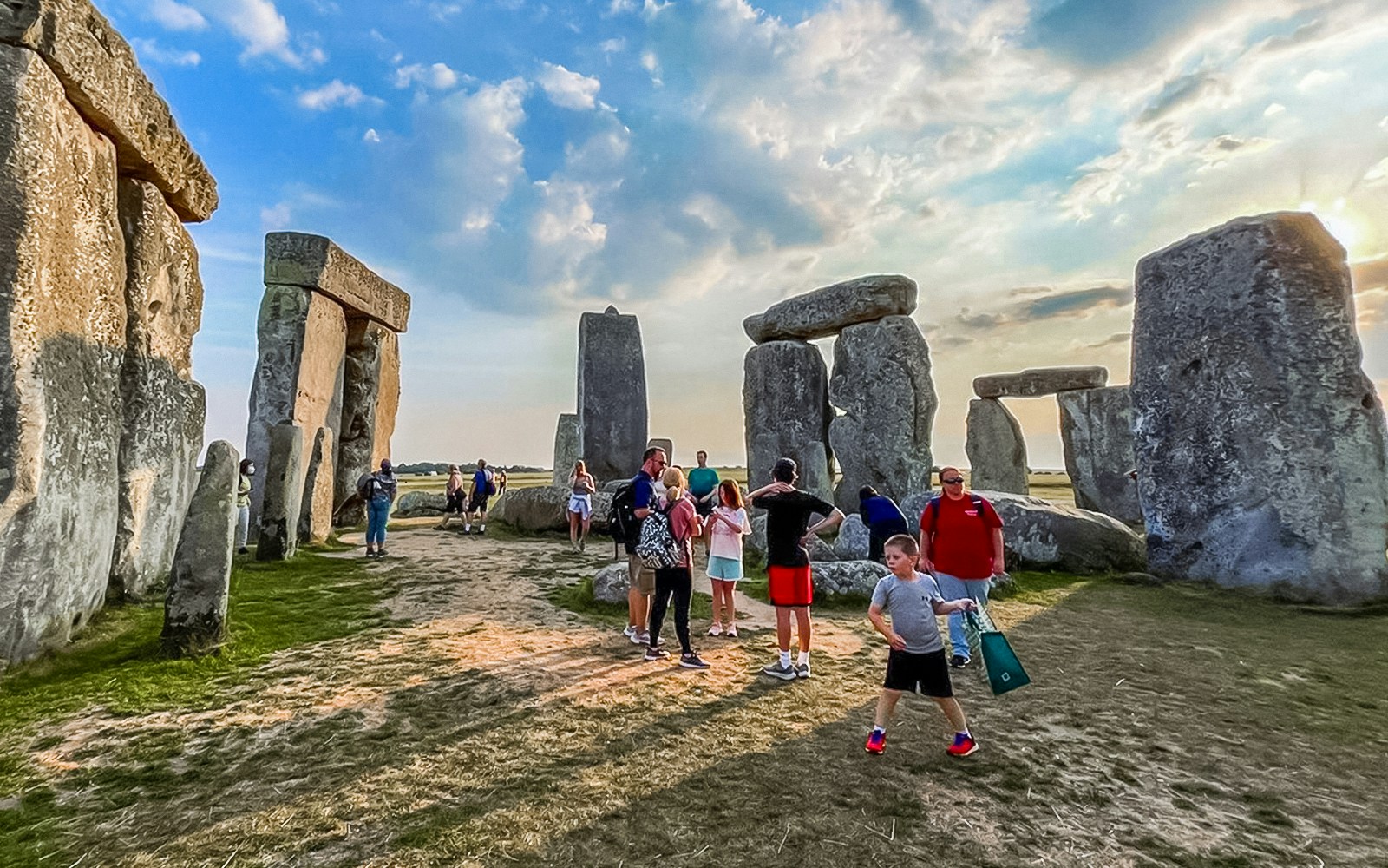 Group of tourists experiencing exclusive walk between the ancient stones at Stonehenge, with a scenic view of the countryside, on a guided tour from London