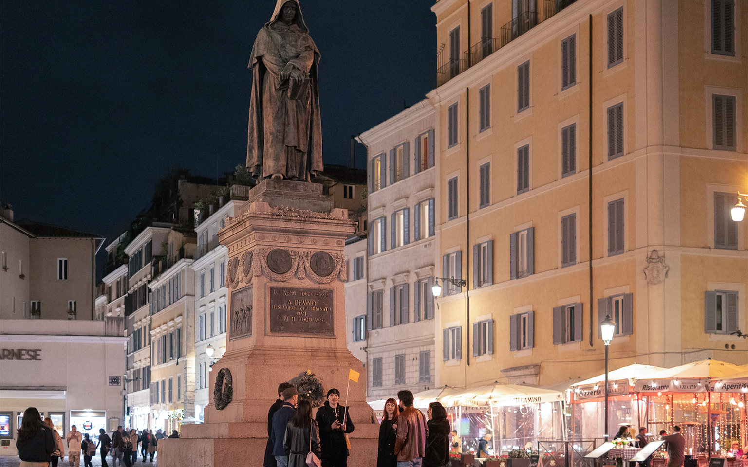 Group gathered at Giordano Bruno statue in Campo de' Fiori, Rome, during haunted ghost tour.