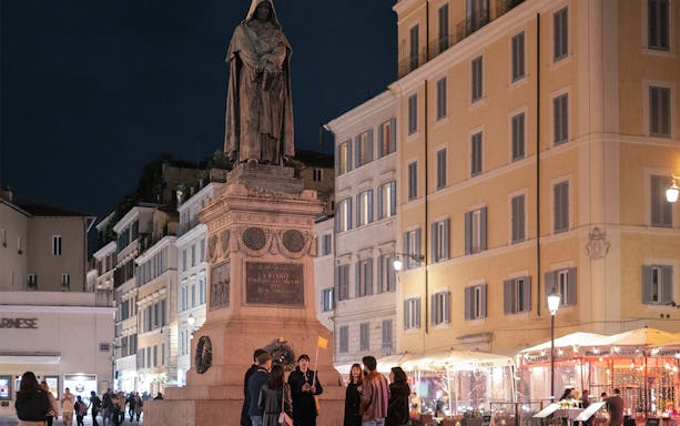 Group gathered at Giordano Bruno statue in Campo de' Fiori, Rome, during haunted ghost tour.