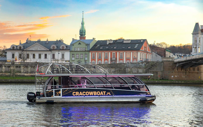 Catamaran with lights on Vistula River during Krakow evening cruise.