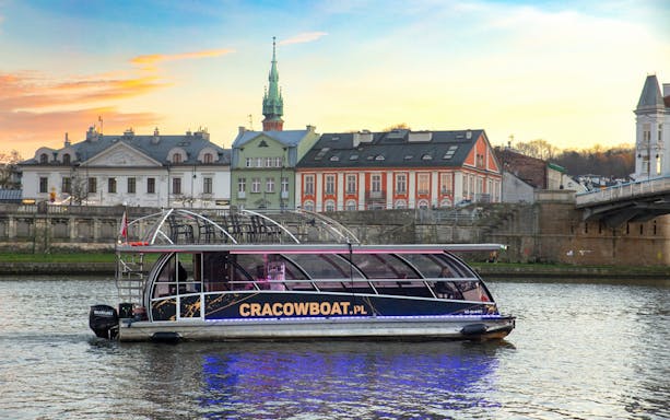 Catamaran with lights on Vistula River during Krakow evening cruise.