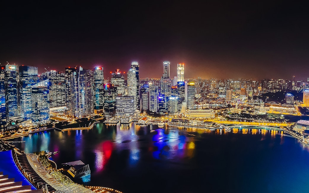 Singapore skyline illuminated at night, viewed from Marina Bay Sands SkyPark Observation Deck.
