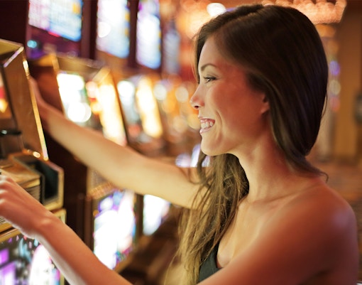 Asian woman playing slot machine in a casino.