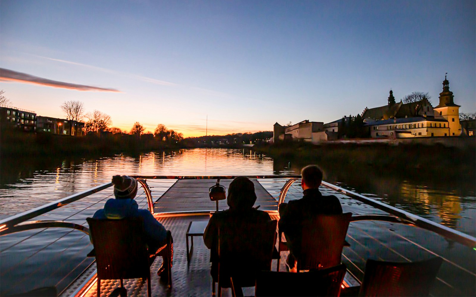 Guests enjoying a nighttime Vistula River cruise on a catamaran in Krakow, Poland.