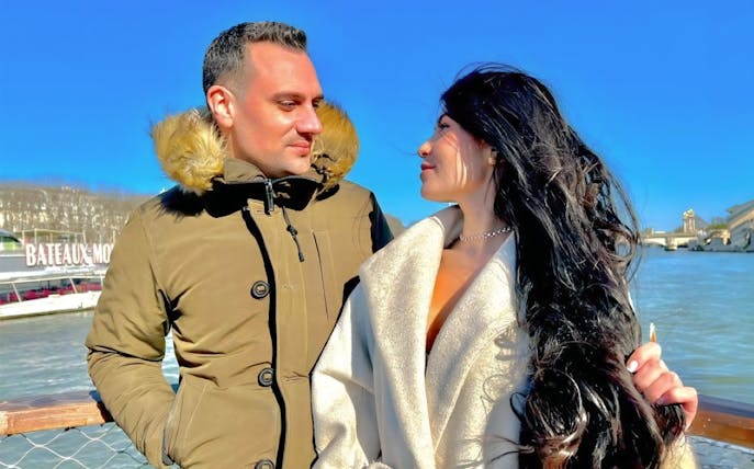 Couple enjoying a morning Seine River cruise in Paris with Bateaux Mouches in the background.