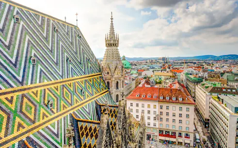 St. Stephen's Cathedral rooftop view in Vienna, featuring colorful patterned tiles and cityscape.