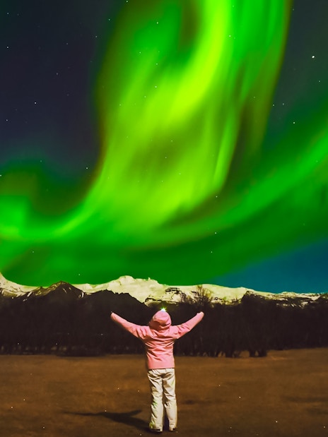 Tourist admiring Northern Lights in Reykjavik, Iceland.