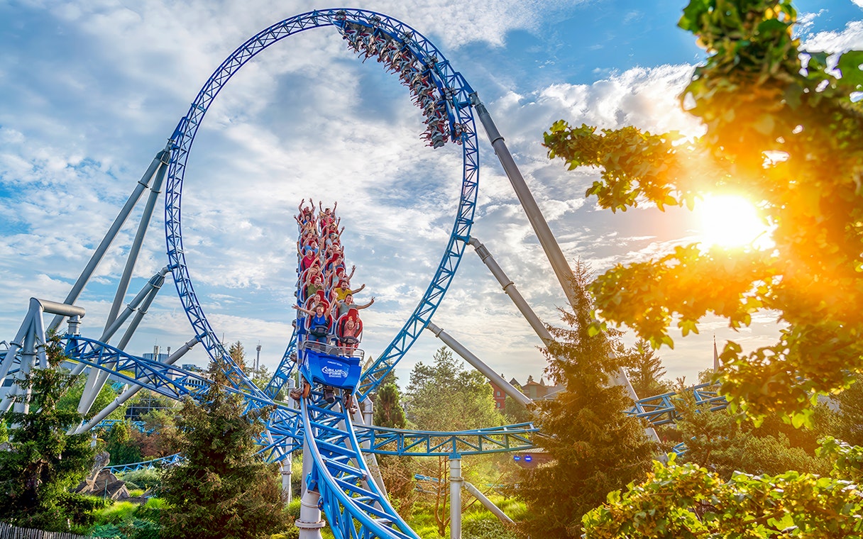 Roller coaster loop with riders at Europa-Park under a sunny sky.