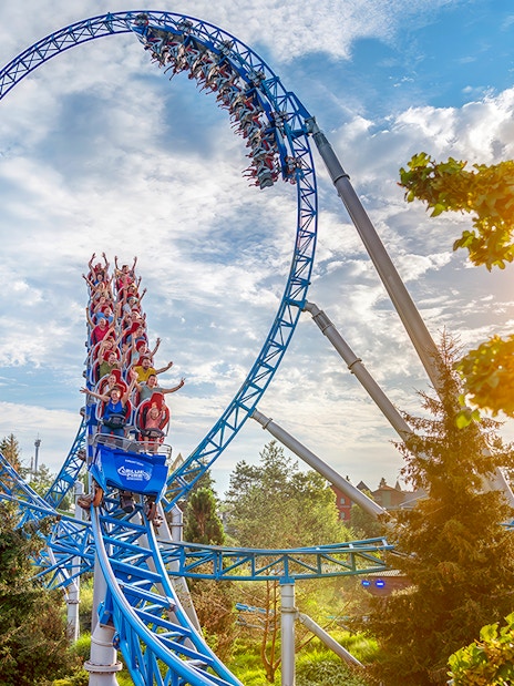 Roller coaster loop with riders at Europa-Park under a sunny sky.