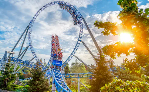 Roller coaster loop with riders at Europa-Park under a sunny sky.