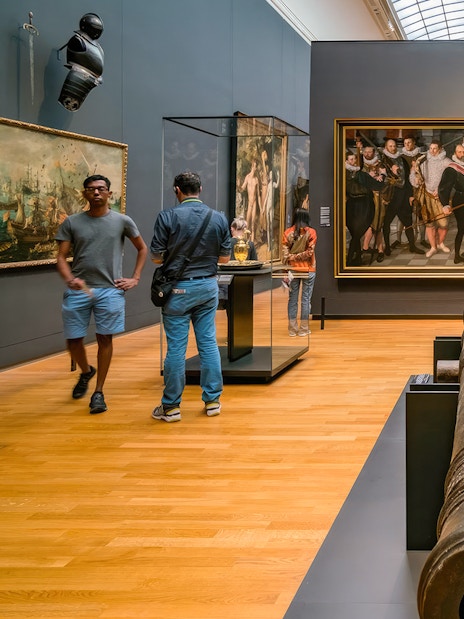 Visitors exploring art and artifacts in a gallery during the First Access Guided Tour of Rijksmuseum.
