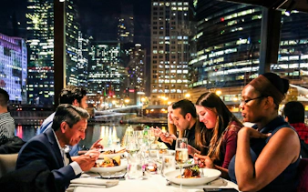 Dining on a Chicago river cruise with city skyline views at night.