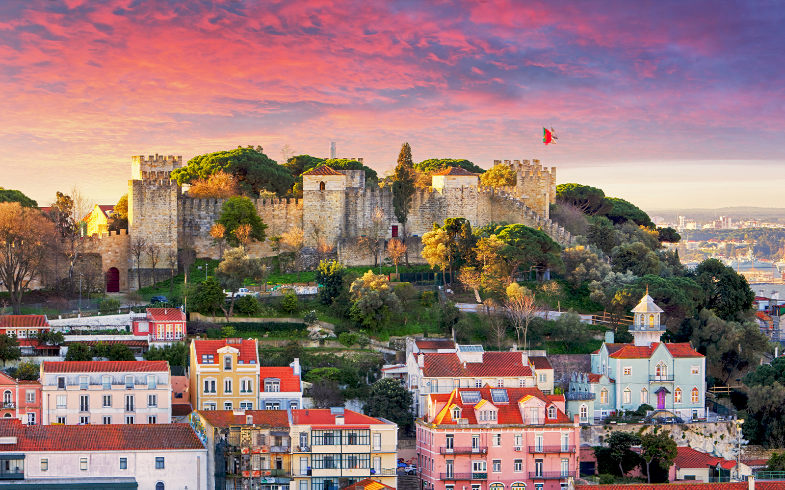 São Jorge Castle in Lisbon at sunset with cityscape in the background.