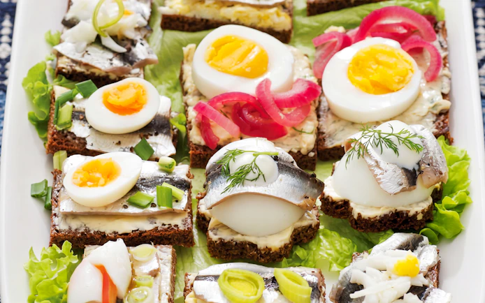 Open-faced sandwiches with herring, boiled eggs, and pickled onions on rye bread, Tallinn food tour.