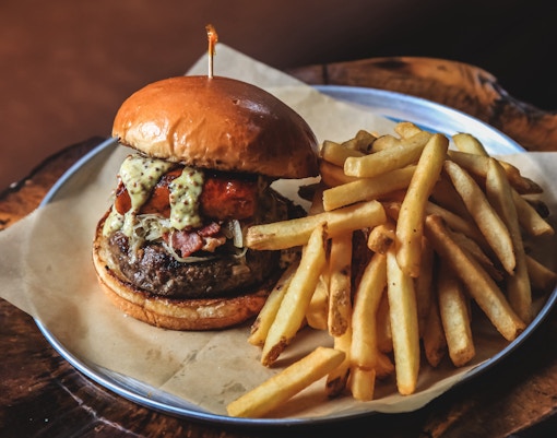 Burger and fries served on a wooden board at a Dali-themed restaurant in Barcelona.