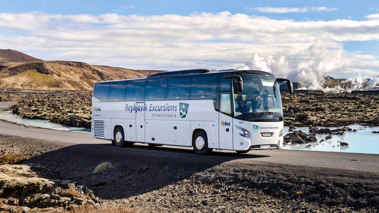 Reykjavik Excursions transfer bus on a scenic road in Iceland.