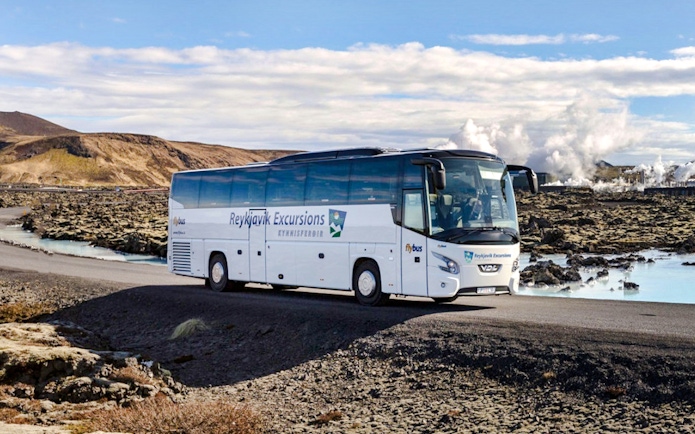 Reykjavik Excursions transfer bus on a scenic road in Iceland.