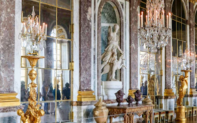 Palace of Versailles interior with ornate chandeliers and classical statue.