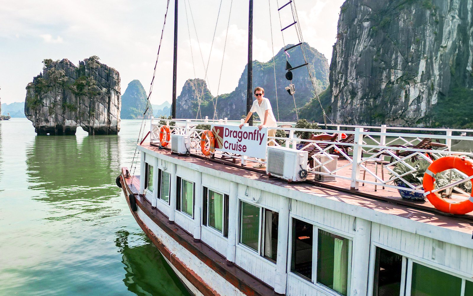 Dragonfly Standard Cruise boat on Halong Bay with limestone karsts in the background.
