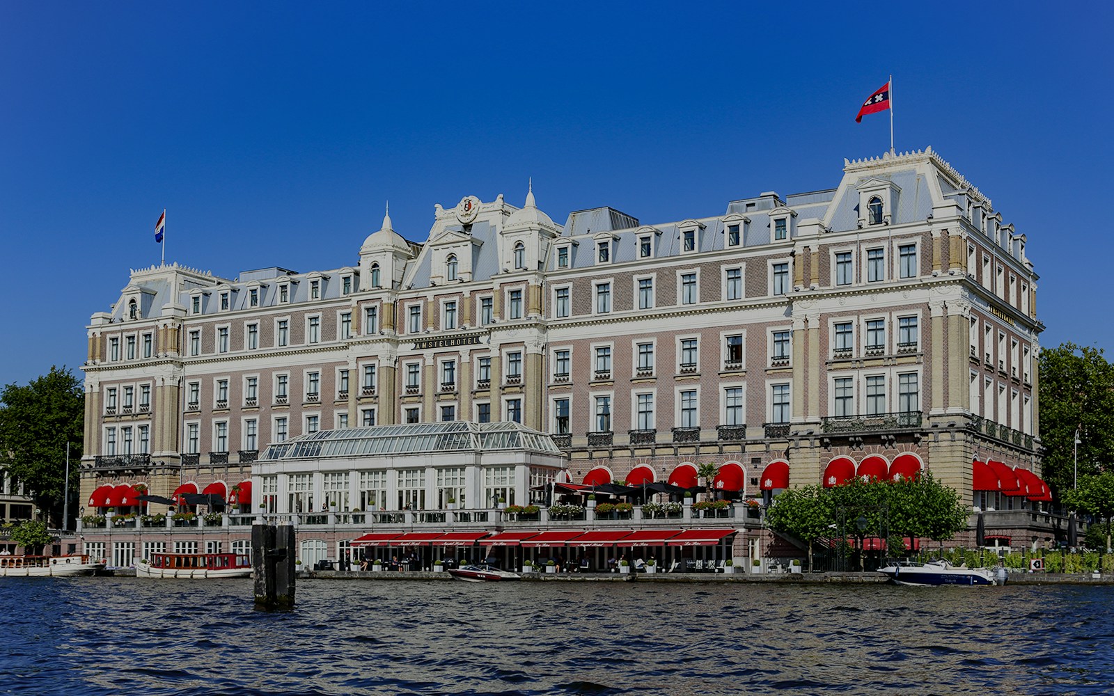 Amstel Hotel in Amsterdam with red awnings along the river.