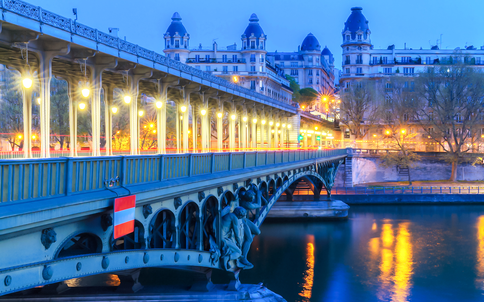 Bir-Hakeim Bridge illuminated at night over the Seine River in Paris.