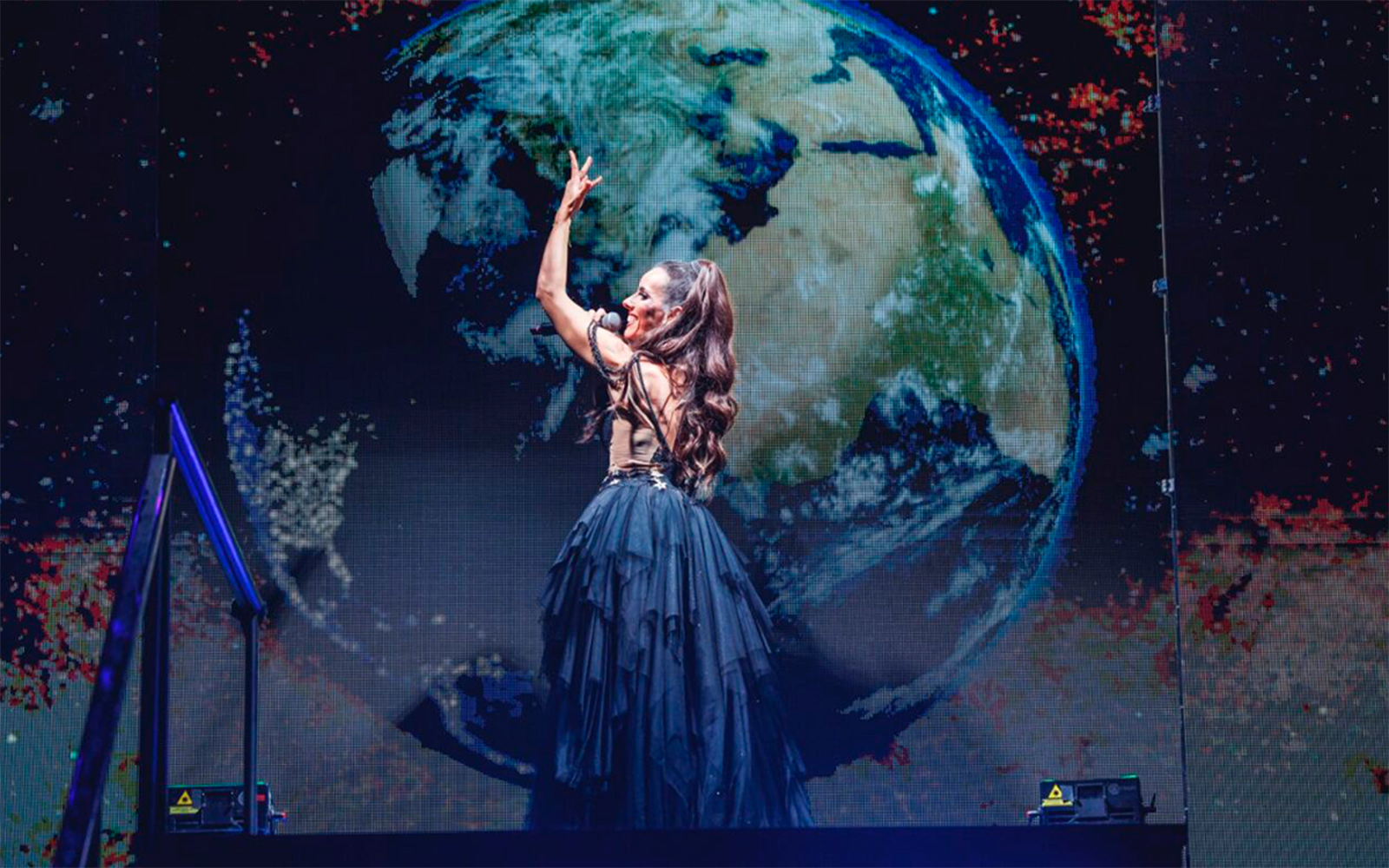 Performer on stage with Earth backdrop, WAH tour.