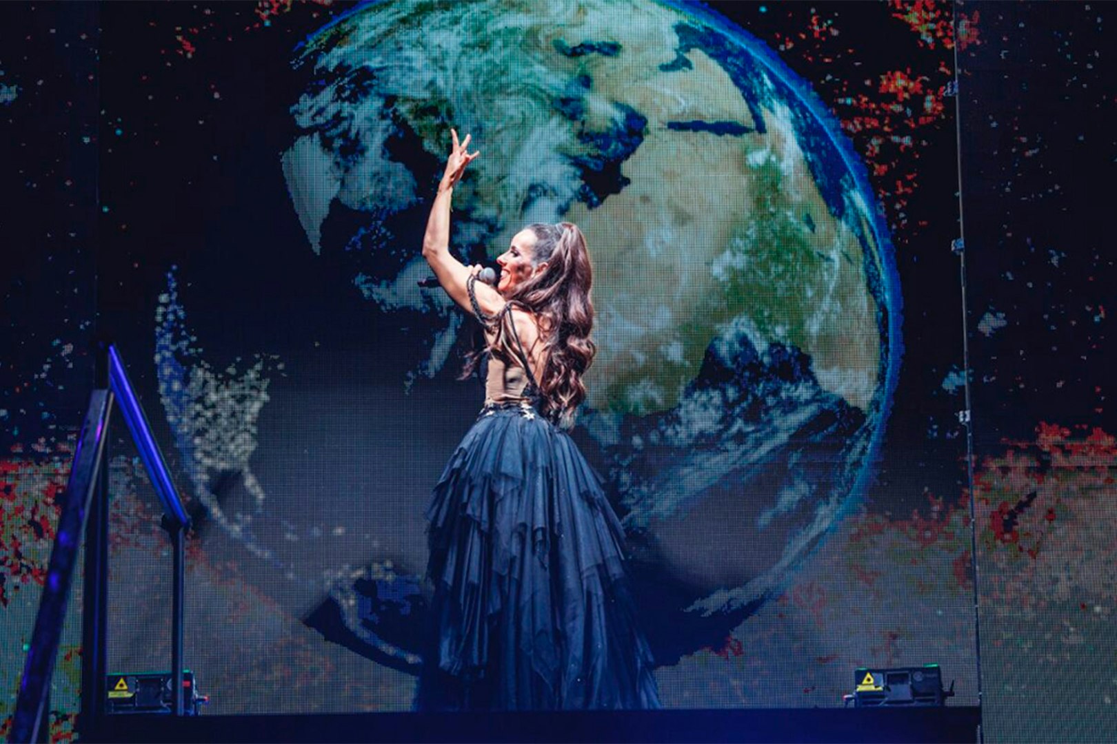 Performer on stage with Earth backdrop, WAH tour.