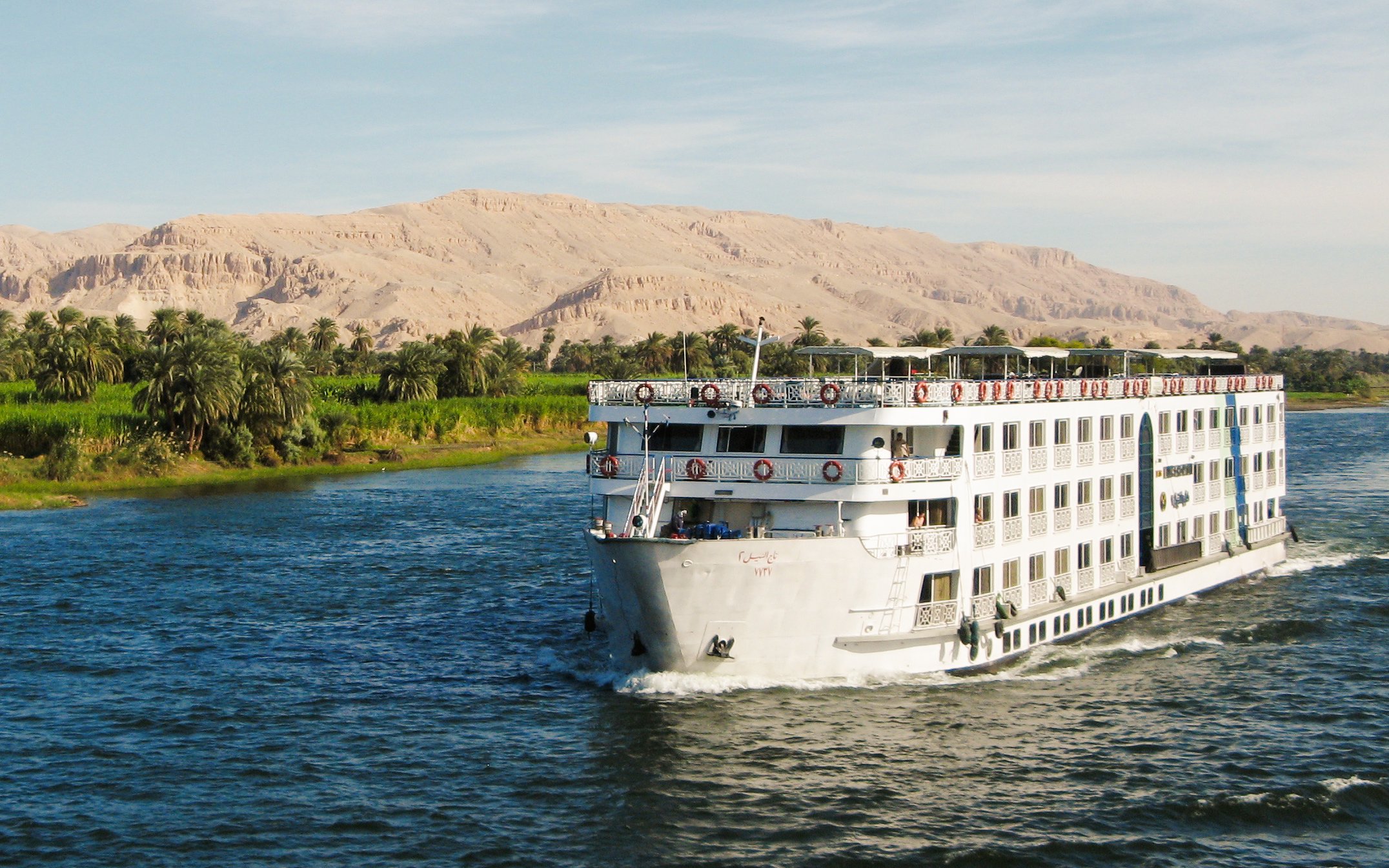 Cruise ship sailing on the River Nile with desert landscape in Egypt.