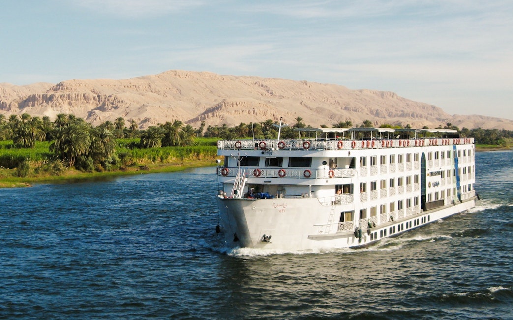 Cruise ship sailing on the River Nile with desert landscape in Egypt.