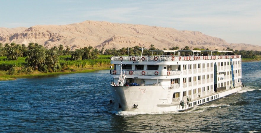 Cruise ship sailing on the River Nile with desert landscape in Egypt.