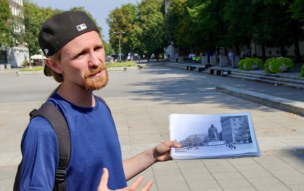 Tour guide in Nowa Huta, Kraków, holding a historical photo during a district tour.