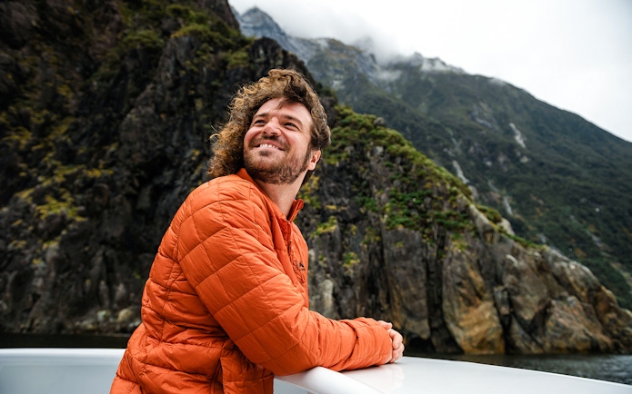 Visitor enjoying the view from a deck at Milford Sound, New Zealand.