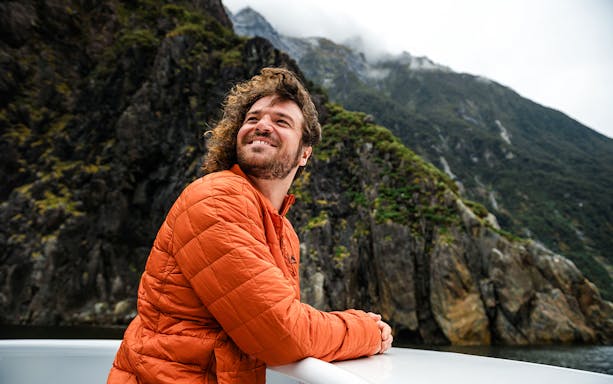 Visitor enjoying the view from a deck at Milford Sound, New Zealand.