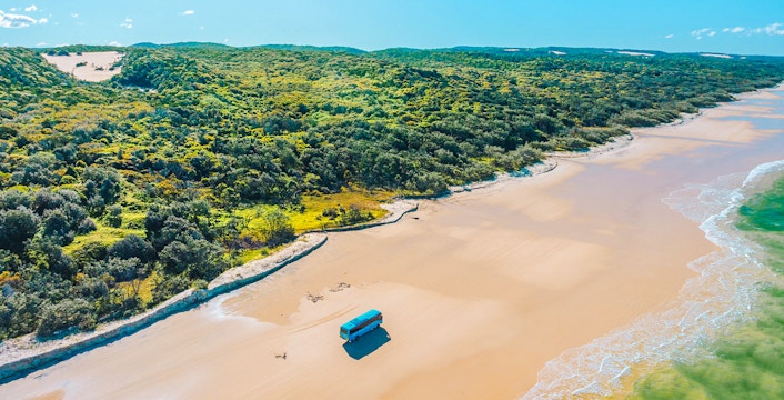 4 wheel drive coach on K'gari's Fraser Island beach, showcasing coastal tour experience.