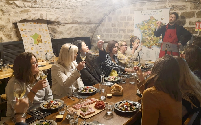People enjoying a cheese and wine tasting at Paroles de Fromagers in Paris, France.