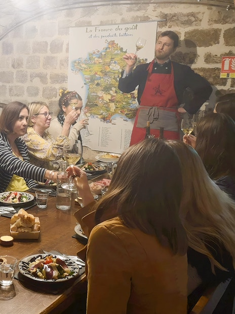 People enjoying a cheese and wine tasting at Paroles de Fromagers in Paris, France.