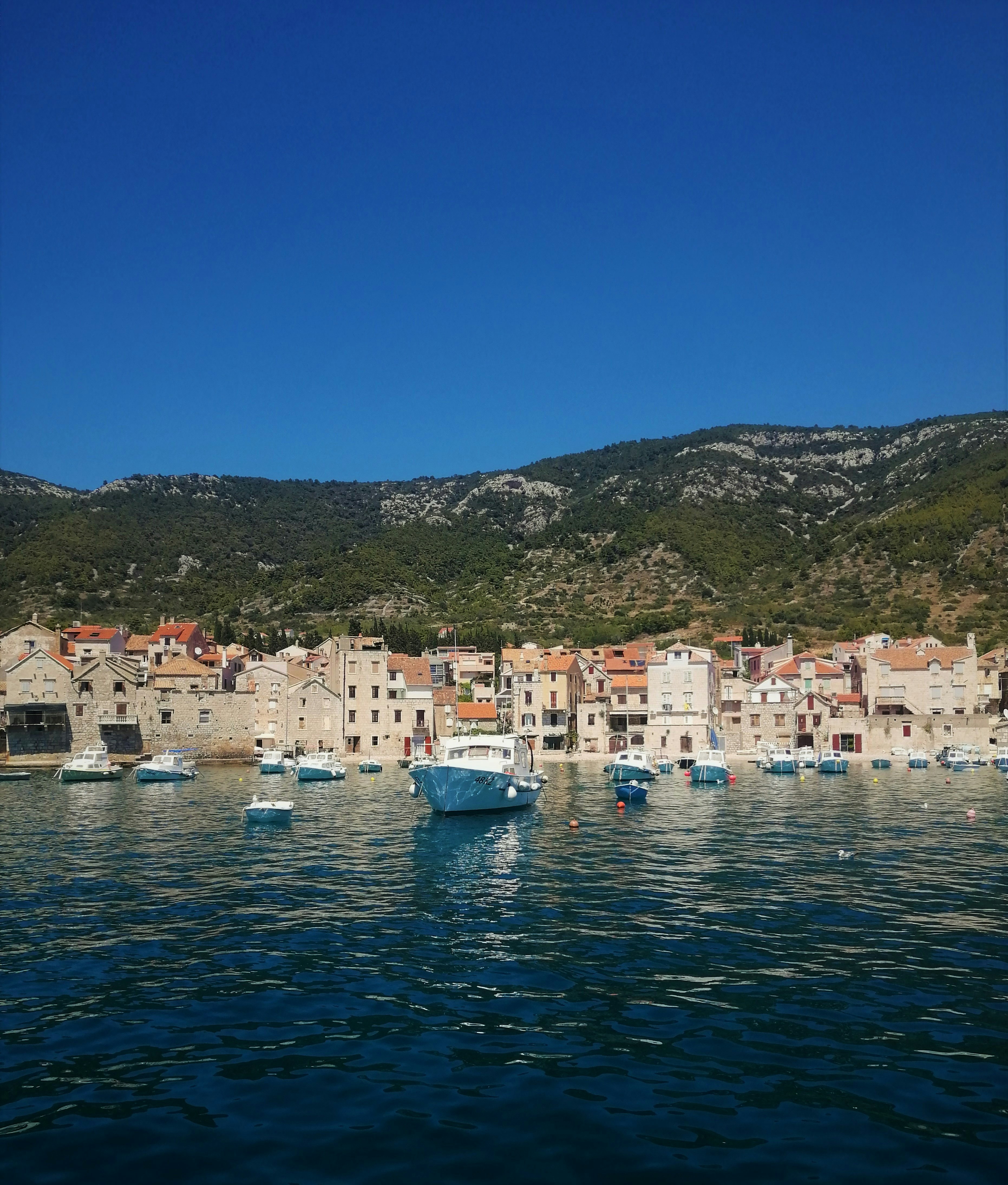 Fishing boats docked at Komiža harbor, Vis Island, Croatia, with traditional stone buildings in the background.