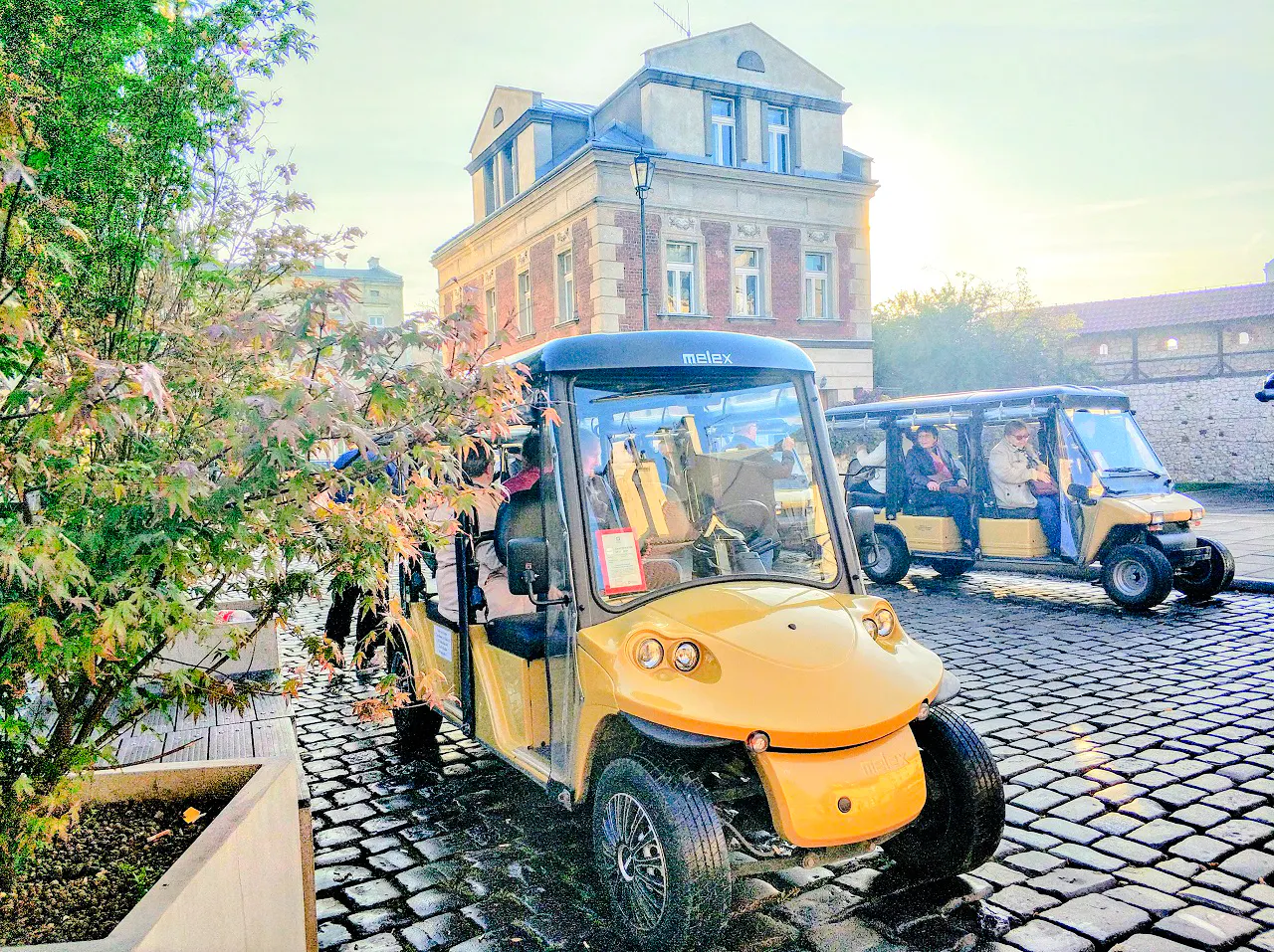 Golf carts on cobblestone street in Krakow's Old Town during a tour.