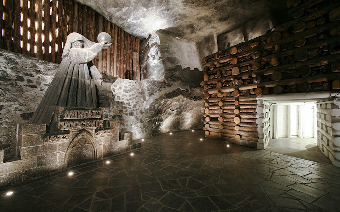 Wieliczka Salt Mine sculpture of a robed figure holding a sphere, surrounded by salt walls.