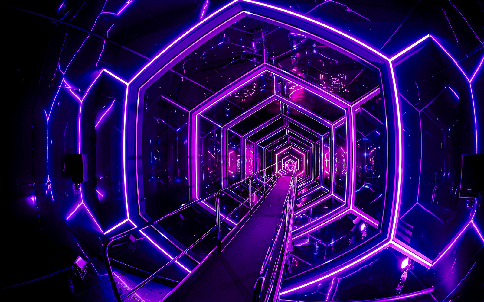 Neon-lit tunnel inside Amaze Amsterdam with geometric patterns.