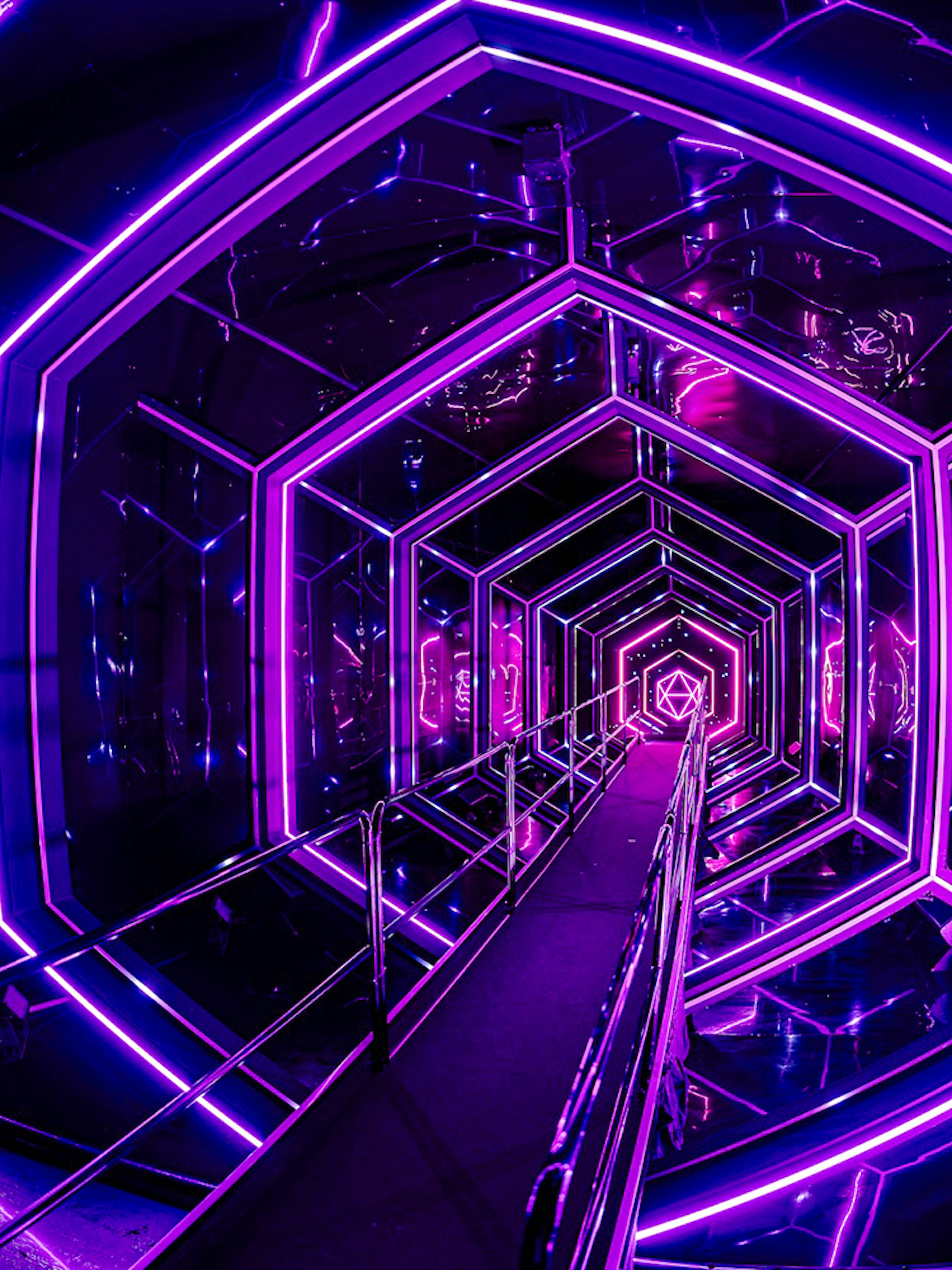 Neon-lit tunnel inside Amaze Amsterdam with geometric patterns.