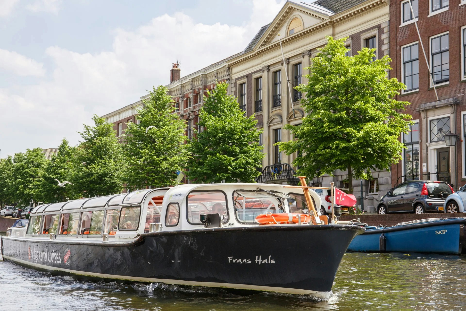 Canal boat cruising past historic buildings in Haarlem.