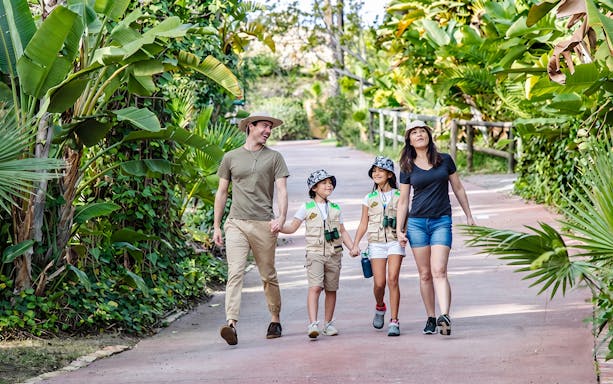 Family walking through lush greenery at Selwo Aventura park, Estepona, Spain.
