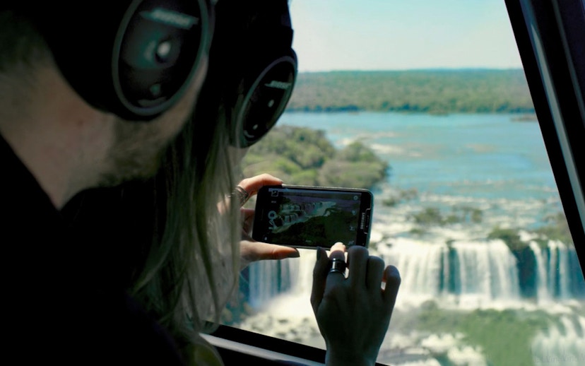 Passengers photographing Iguazu Falls from helicopter window.