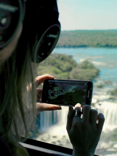 Passengers photographing Iguazu Falls from helicopter window.