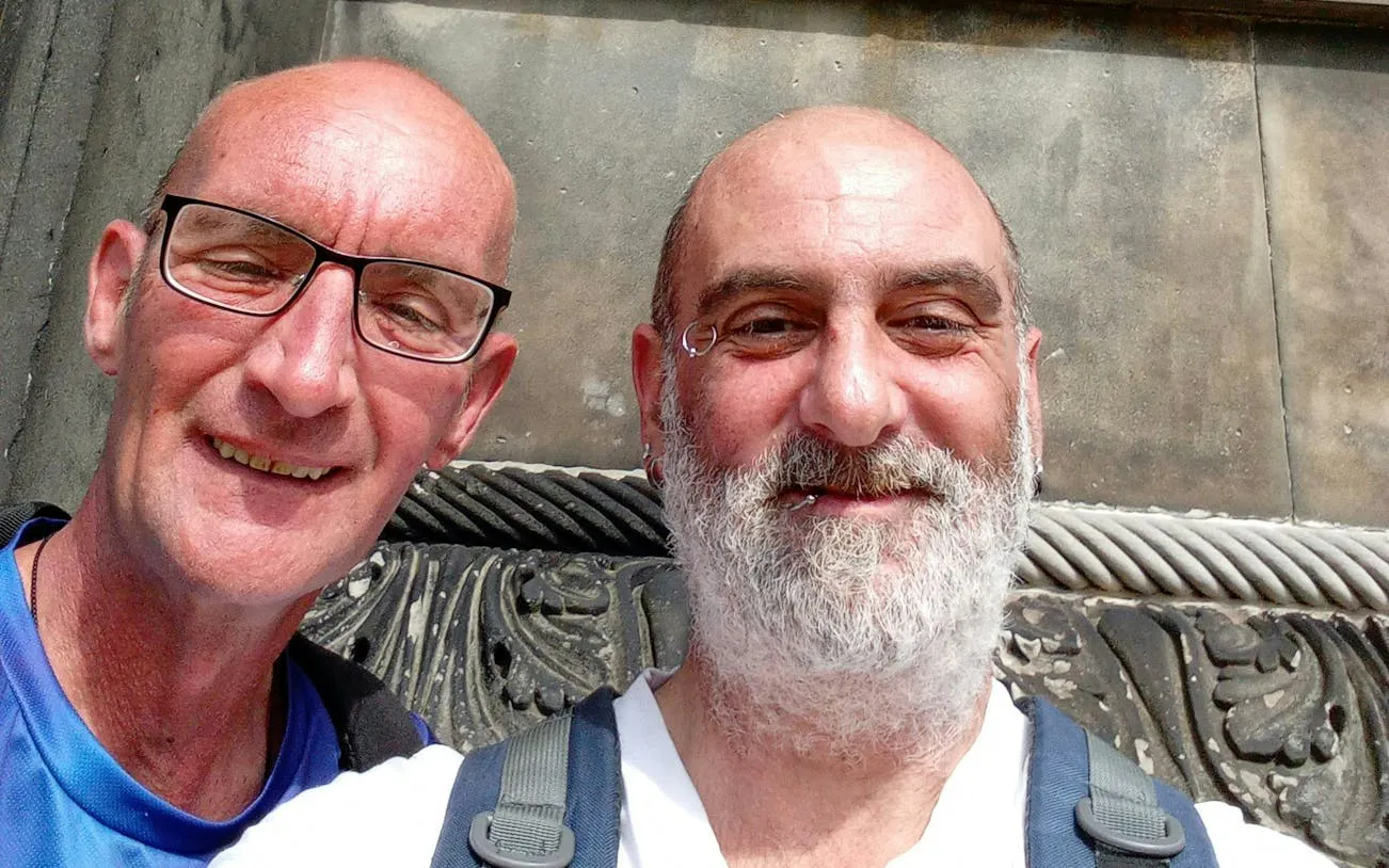 Two people smiling in front of a historic building in Edinburgh during a murder mystery city exploration game.